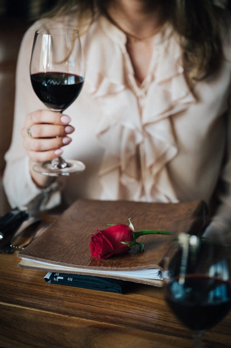 Girl drinking cold drink with red rose on table on Valentine dinner